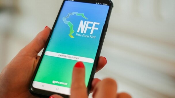 M&atilde;o segura celular. Na tela, est&aacute; o aplicativo Nota Fiscal F&aacute;cil